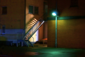 Eine Feuerleiter zwischen zwei Häusern, nachts, die Ecke wird von einer Laterne beleuchtet